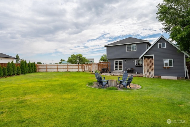 rear view of house with a yard and a fire pit