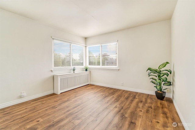 empty room with radiator heating unit and wood-type flooring