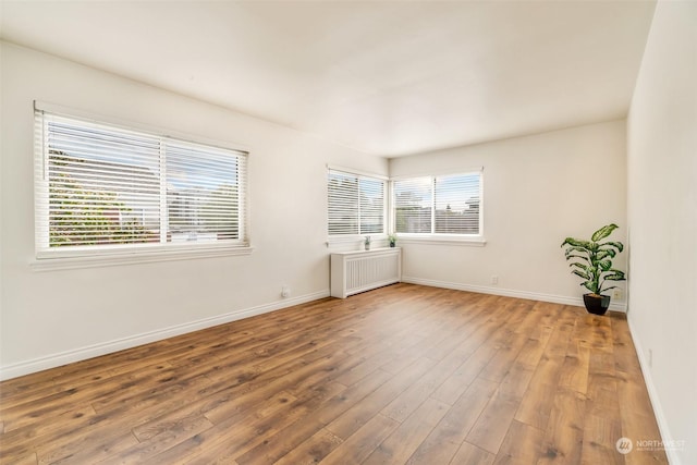 spare room with hardwood / wood-style floors and radiator heating unit