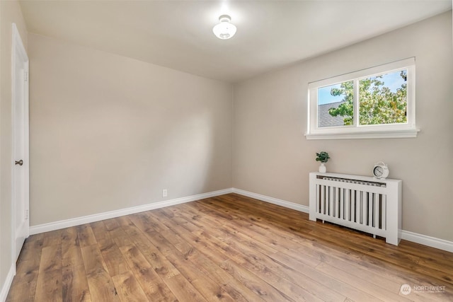 spare room featuring radiator and light hardwood / wood-style floors