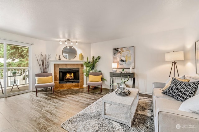 living room featuring a tile fireplace, hardwood / wood-style floors, and a textured ceiling