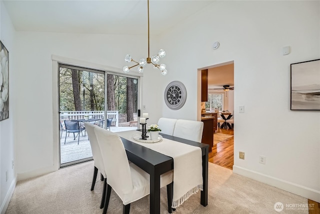 dining room with light carpet, a healthy amount of sunlight, and high vaulted ceiling