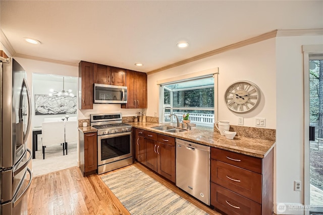 kitchen featuring stainless steel appliances, plenty of natural light, a sink, and light wood-style flooring