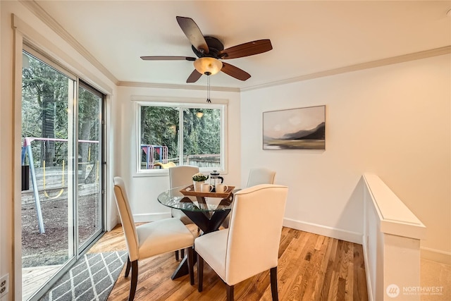 dining room featuring light wood finished floors, a ceiling fan, baseboards, and crown molding