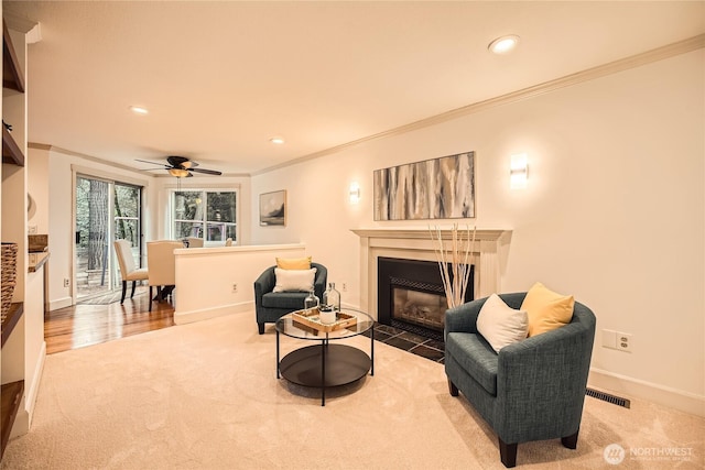 sitting room with crown molding, carpet flooring, a fireplace with flush hearth, and baseboards