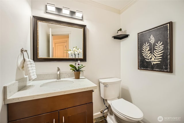 half bathroom with ornamental molding, baseboards, vanity, and toilet