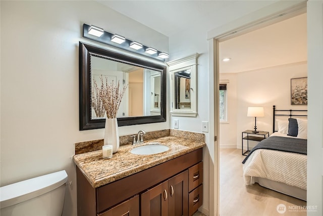 bathroom with toilet, baseboards, wood finished floors, and vanity