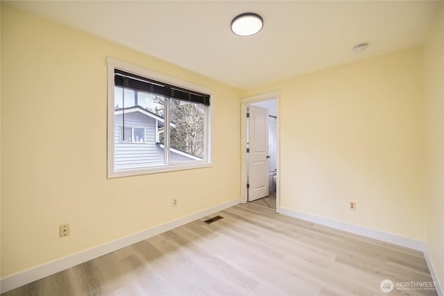 spare room featuring light wood-style floors, visible vents, and baseboards