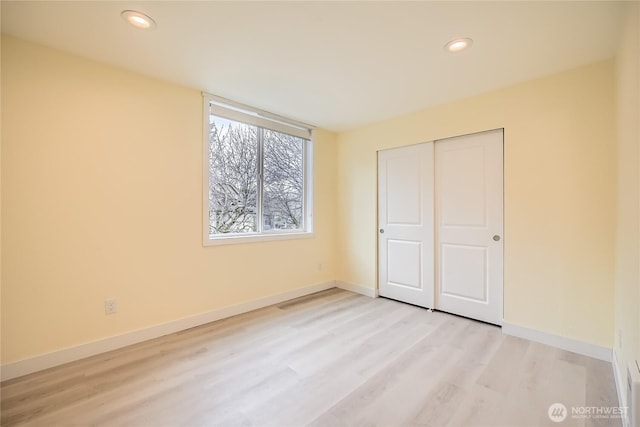 unfurnished bedroom with recessed lighting, a closet, light wood-type flooring, and baseboards