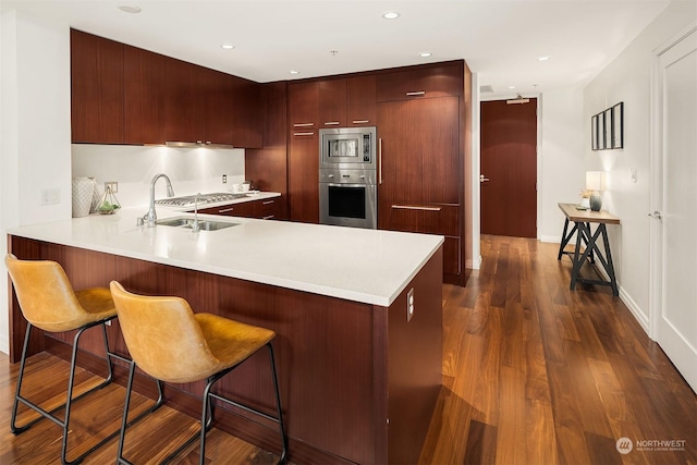 kitchen with appliances with stainless steel finishes, a breakfast bar, sink, and kitchen peninsula