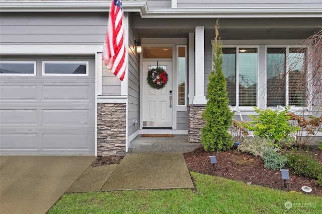 view of exterior entry with a garage and a porch