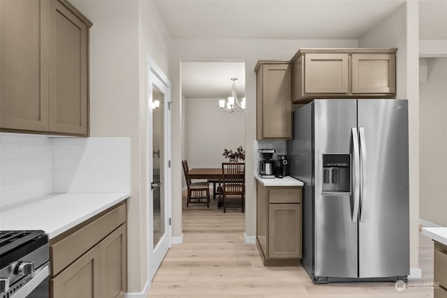 kitchen featuring decorative backsplash, stainless steel appliances, a chandelier, and light wood-type flooring