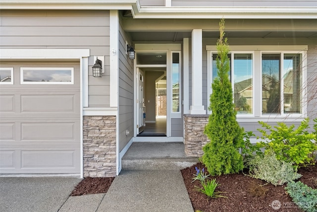 view of exterior entry featuring stone siding, a porch, and a garage