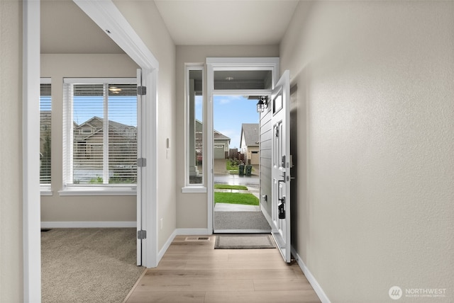 entryway featuring light wood finished floors, baseboards, and visible vents
