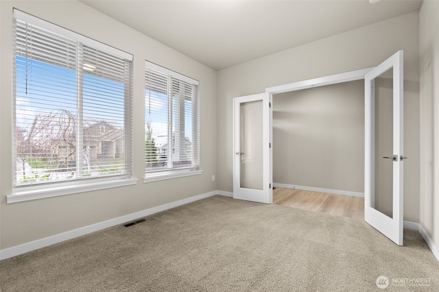 unfurnished bedroom featuring baseboards, french doors, visible vents, and light colored carpet