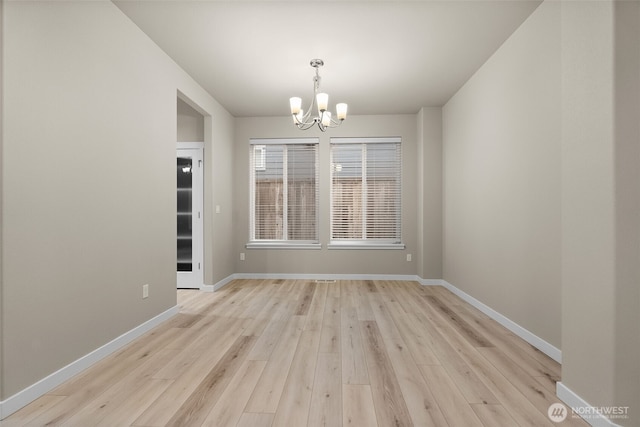 unfurnished dining area with light wood finished floors, a notable chandelier, and baseboards