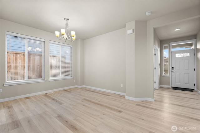 interior space featuring an inviting chandelier, light wood-style floors, and baseboards