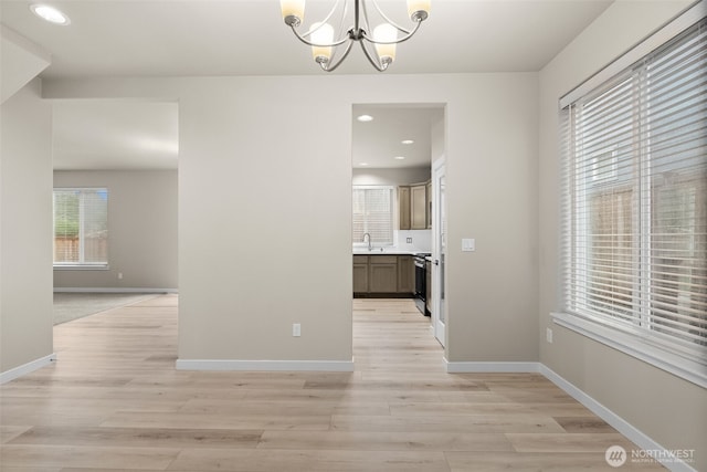 unfurnished dining area featuring light wood finished floors, a chandelier, baseboards, and recessed lighting