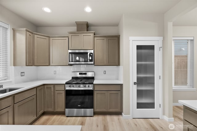 kitchen featuring light countertops, appliances with stainless steel finishes, tasteful backsplash, and light wood-style floors