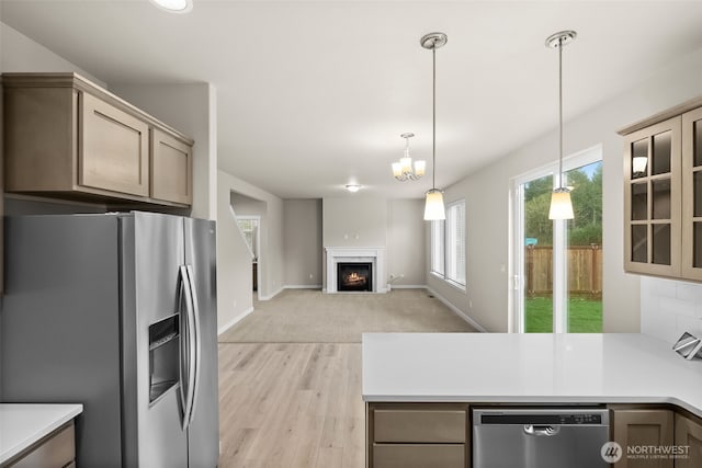 kitchen featuring a peninsula, stainless steel appliances, light wood-type flooring, pendant lighting, and light countertops