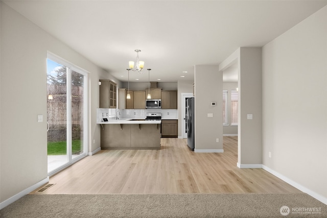 kitchen with stainless steel appliances, visible vents, an inviting chandelier, light wood finished floors, and light countertops