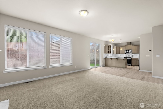 unfurnished living room with baseboards, a healthy amount of sunlight, and visible vents