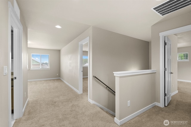 corridor featuring a healthy amount of sunlight, an upstairs landing, visible vents, carpet floors, and baseboards
