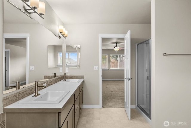 bathroom with a sink, a stall shower, double vanity, and baseboards
