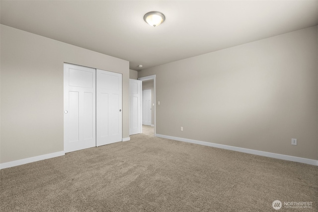unfurnished bedroom featuring light carpet, baseboards, and a closet
