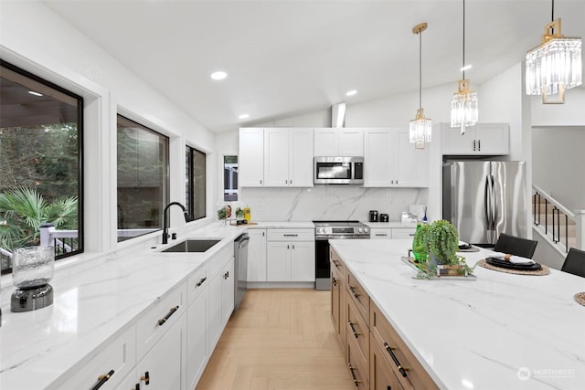 kitchen with sink, white cabinetry, appliances with stainless steel finishes, light stone countertops, and decorative backsplash