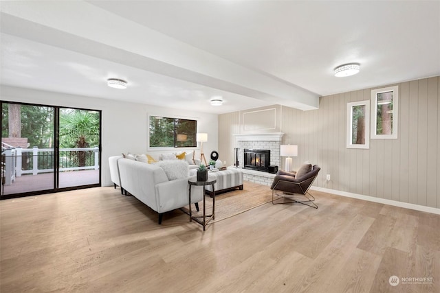 living room featuring a brick fireplace, light hardwood / wood-style flooring, and wood walls