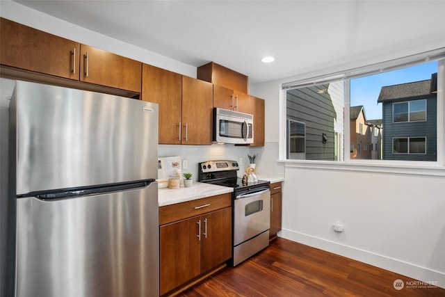 kitchen with appliances with stainless steel finishes, backsplash, and dark hardwood / wood-style flooring