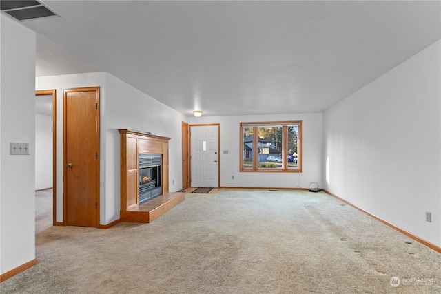 unfurnished living room with a tile fireplace and light carpet