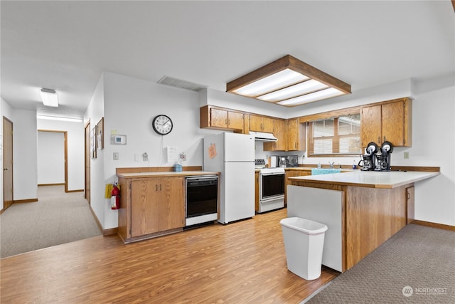 kitchen with sink, white appliances, light hardwood / wood-style floors, and kitchen peninsula