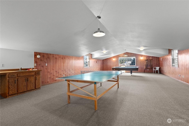 rec room featuring light colored carpet, sink, wooden walls, and vaulted ceiling