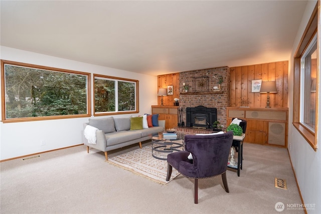 carpeted living room featuring wood walls, a wood stove, and a wealth of natural light