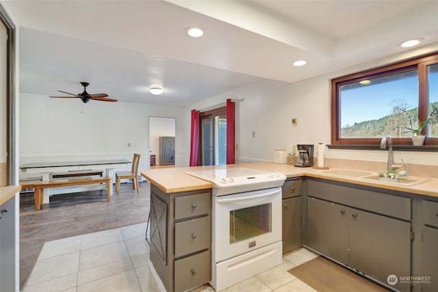 kitchen with white range with electric stovetop, gray cabinetry, a peninsula, and a sink