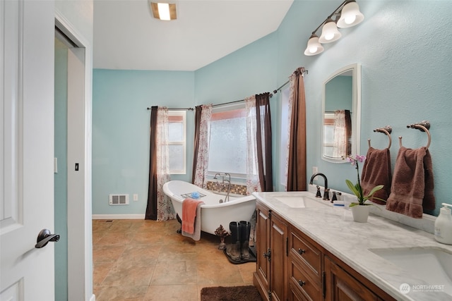 bathroom featuring a sink, a freestanding tub, visible vents, and double vanity