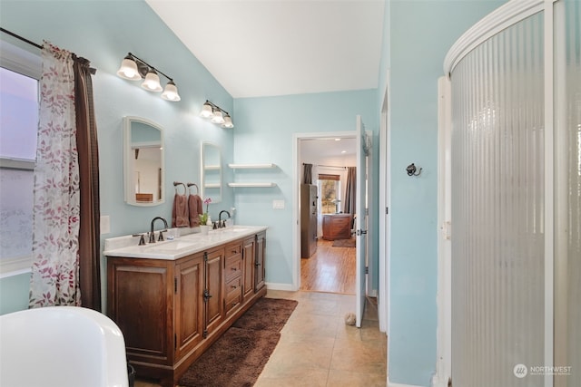 full bathroom featuring a sink, a freestanding bath, double vanity, and tile patterned floors