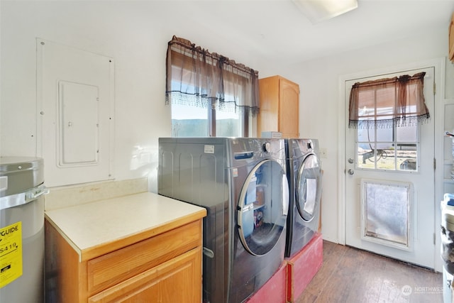 clothes washing area featuring wood finished floors, electric panel, separate washer and dryer, cabinet space, and water heater