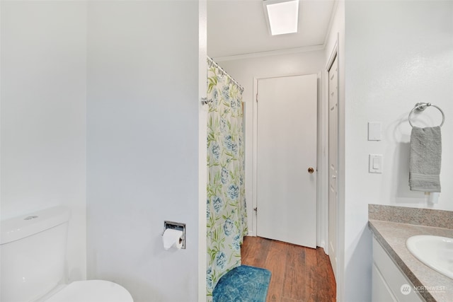 bathroom with toilet, vanity, and wood finished floors