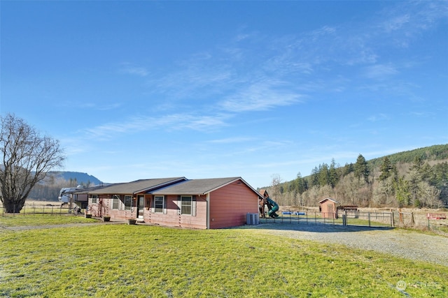 view of home's exterior with fence, a yard, a mountain view, gravel driveway, and central AC unit