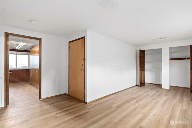 550 SW Waterloo Ave, Oak Harbor, WA 98277 - unfurnished bedroom featuring brick wall, two closets, and light hardwood / wood-style flooring