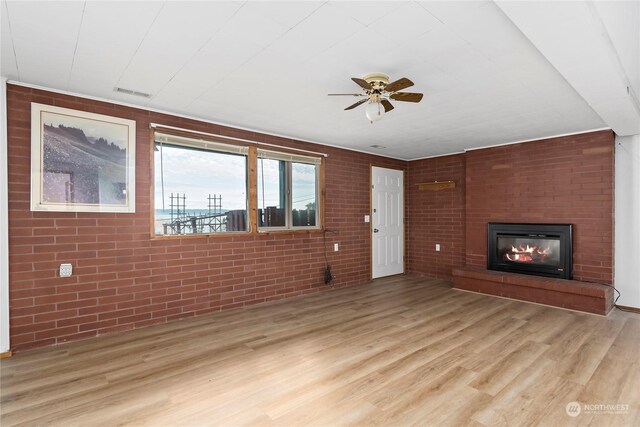 550 SW Waterloo Ave, Oak Harbor, WA 98277 - unfurnished living room with ceiling fan, brick wall, and light wood-type flooring