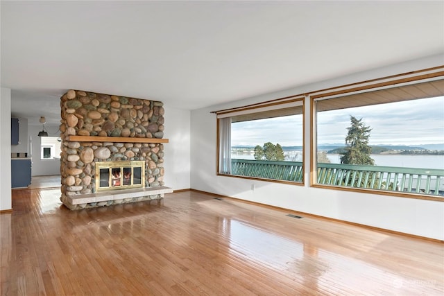 550 SW Waterloo Ave, Oak Harbor, WA 98277 - unfurnished living room with hardwood / wood-style floors, a stone fireplace, and a water view