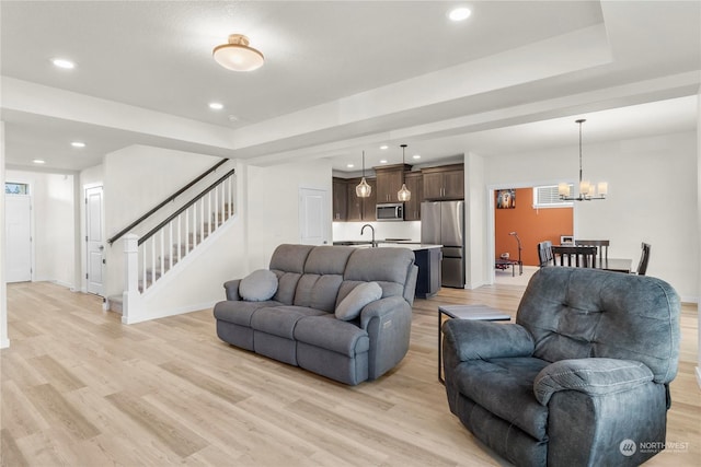 living room with light hardwood / wood-style floors and a notable chandelier