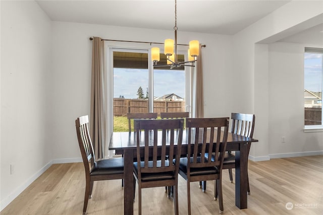 dining space with an inviting chandelier, a healthy amount of sunlight, and light hardwood / wood-style flooring