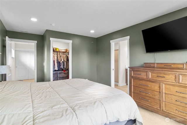 bedroom featuring light carpet, a spacious closet, and a closet