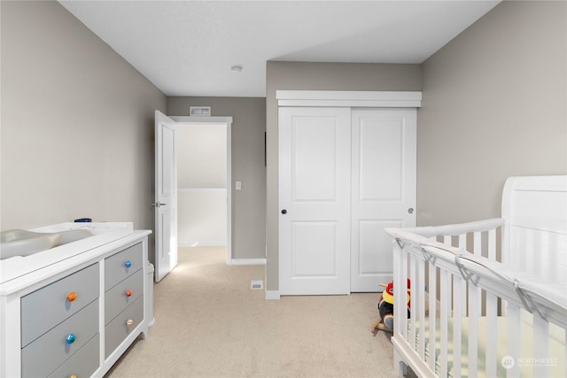 bedroom with a crib, light carpet, and a closet