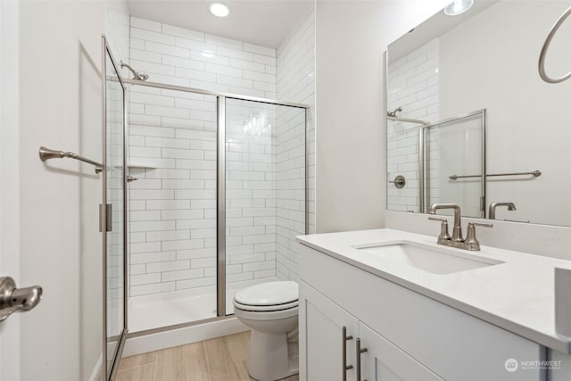 bathroom featuring hardwood / wood-style flooring, vanity, toilet, and an enclosed shower